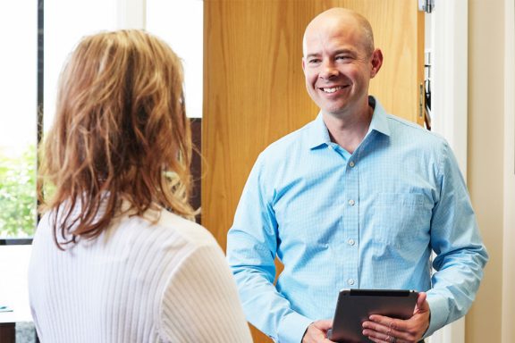 A man and woman in an office looking at each other. The man is holding an iPad